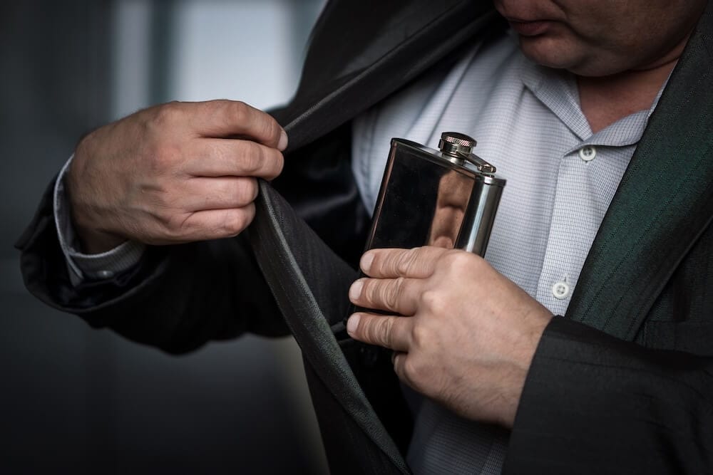 man putting flask in suit jacket
